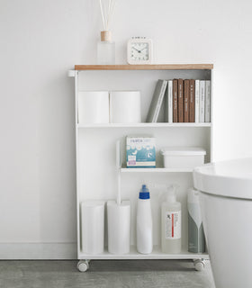 Front view of white Rolling Storage Cart displaying cleaning supplies, toilet paper, and books in bathroom by Yamazaki Home. view 4