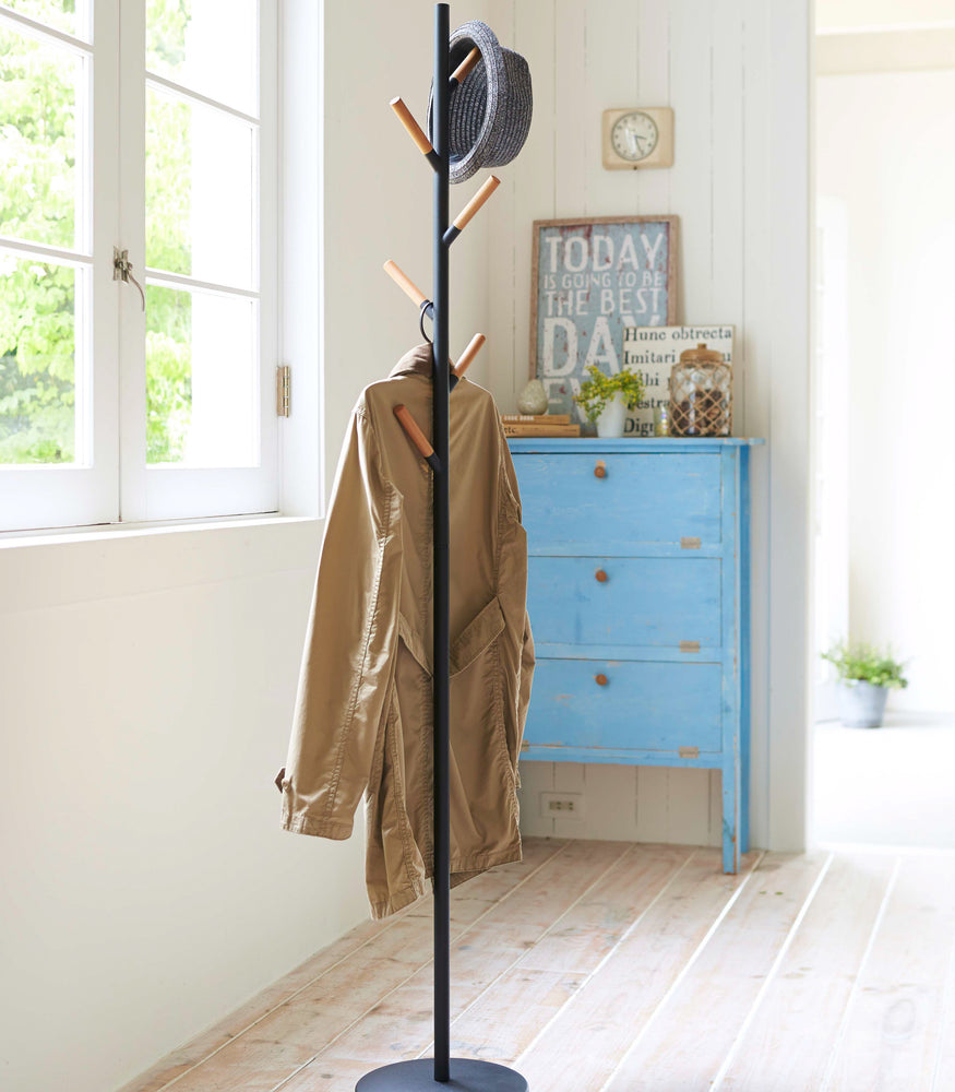 View 8 - Front view of black Freestanding Coat Rack holding jacket and hat by Yamazaki Home.