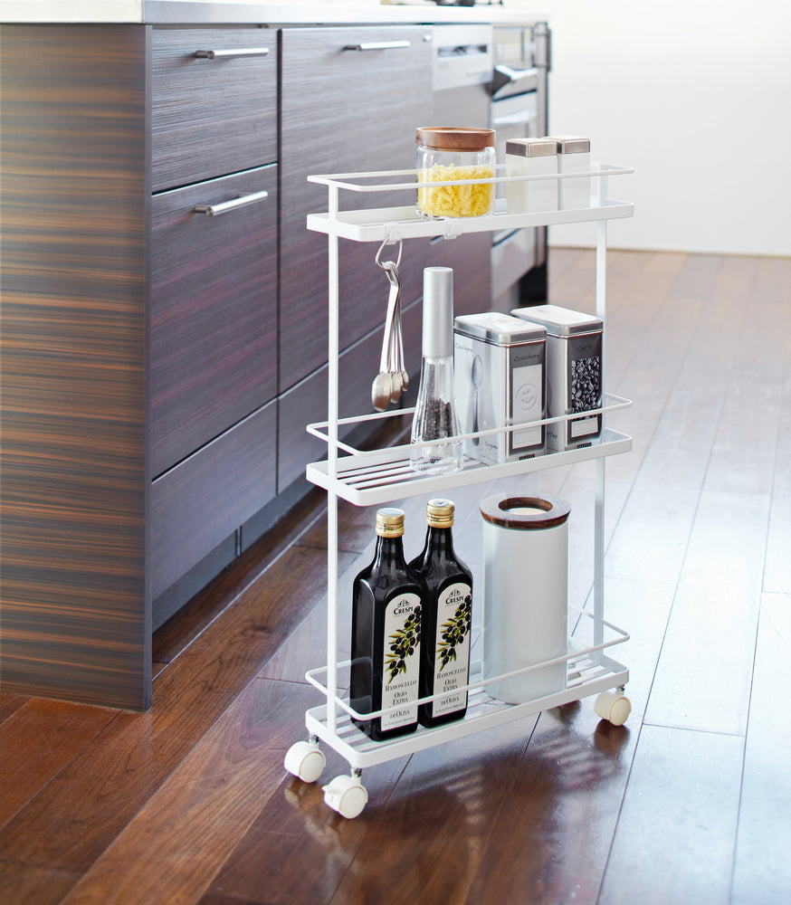 View 3 - White Rolling Cart holding spices and oils in kitchen by Yamazaki Home.