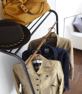 Close up side view of black Leaning Coat Rack with Shelf holding hat, bag, and clothes in bedroom by Yamazaki Home. view 6