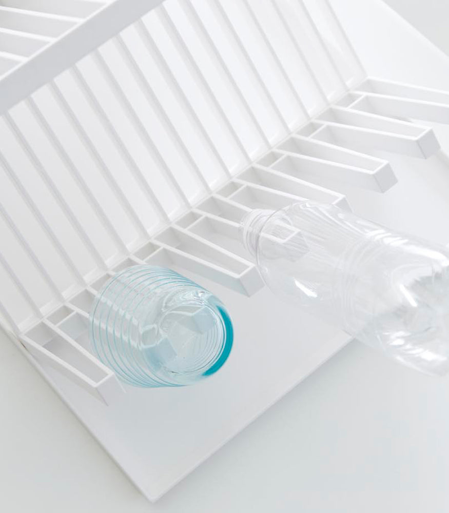 View 5 - Aerial view of white X-Shaped Dish Rack holding cup and bottle on white surface by Yamazaki Home.