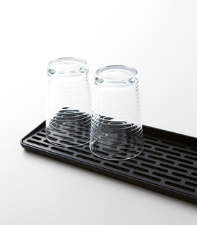 Close up view of black Sink Drainer Tray holding glasses on white background by Yamazaki Home. view 9