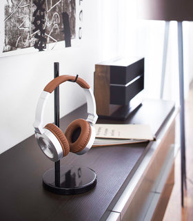 Black Headphone Stand holding headphones on bureau by Yamazaki Home. view 6