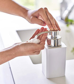 White Foaming Soap Dispenser dispensing soap on bath countertop by Yamazaki Home. view 3