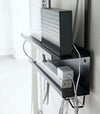 Side view of black Wall-Mount Cable and Router Storage Rack holding routers and power cord by Yamazaki Home.