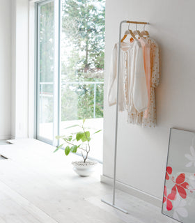 White Slim Leaning Coat Rack holding dresses and blouse by Yamazaki Home. view 2
