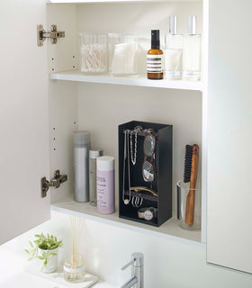 A white medicine cabinet is open to display the inside contents. Sunlight is focused on the right upper corner. Below is a bathroom sink with a silver faucet. On the sinks ledge is a small plant and oil diffuser. view 16