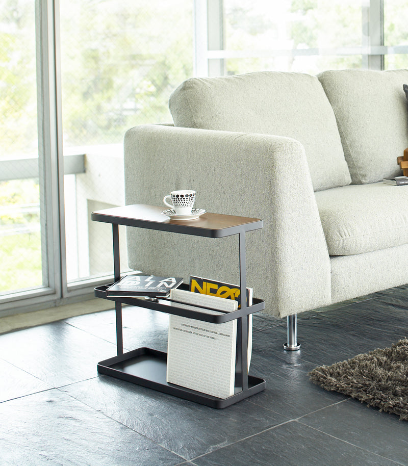Black End Table holding coffee cup and books in living room by Yamazaki Home.