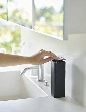 Side view of black One-Handed Push Soap Dispenser on bathroom sink countertop by Yamazaki Home. view 9