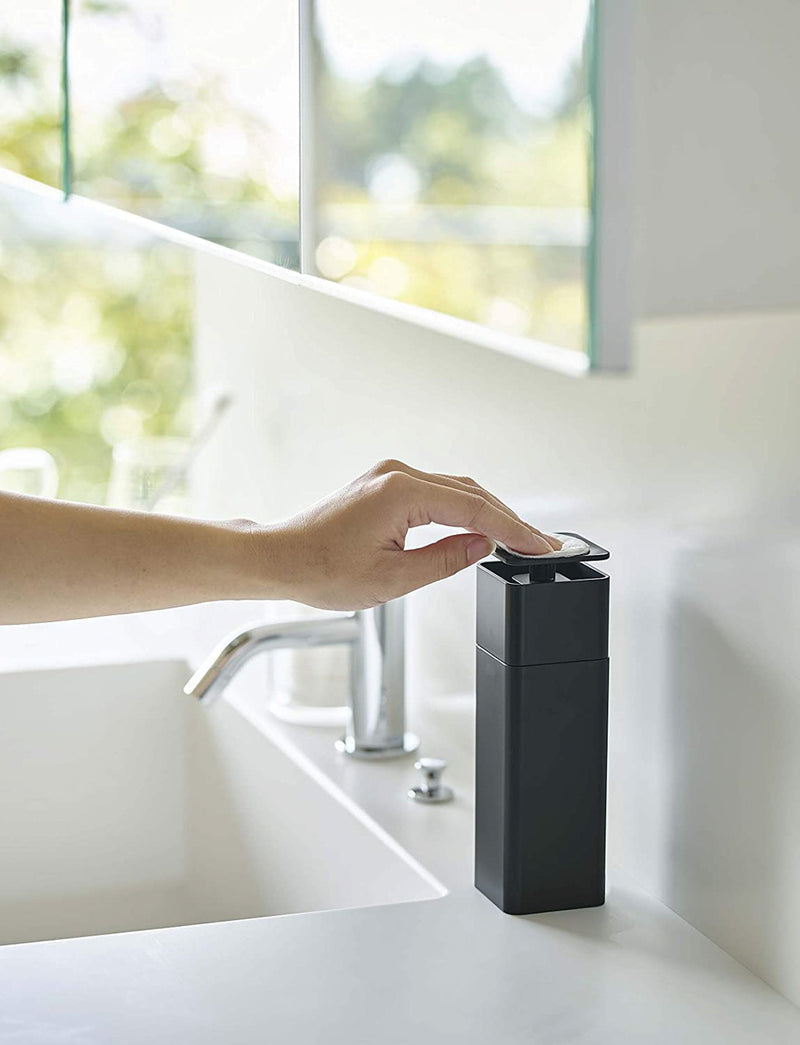 Side view of black One-Handed Push Soap Dispenser on bathroom sink countertop by Yamazaki Home.