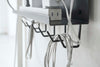 Close up side view of black Wall-Mount Cable and Router Storage Rack's hooks holding cord by Yamazaki Home.