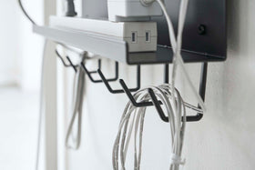 Close up side view of black Wall-Mount Cable and Router Storage Rack's hooks holding cord by Yamazaki Home. view 12