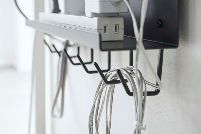 Close up side view of black Wall-Mount Cable and Router Storage Rack's hooks holding cord by Yamazaki Home.