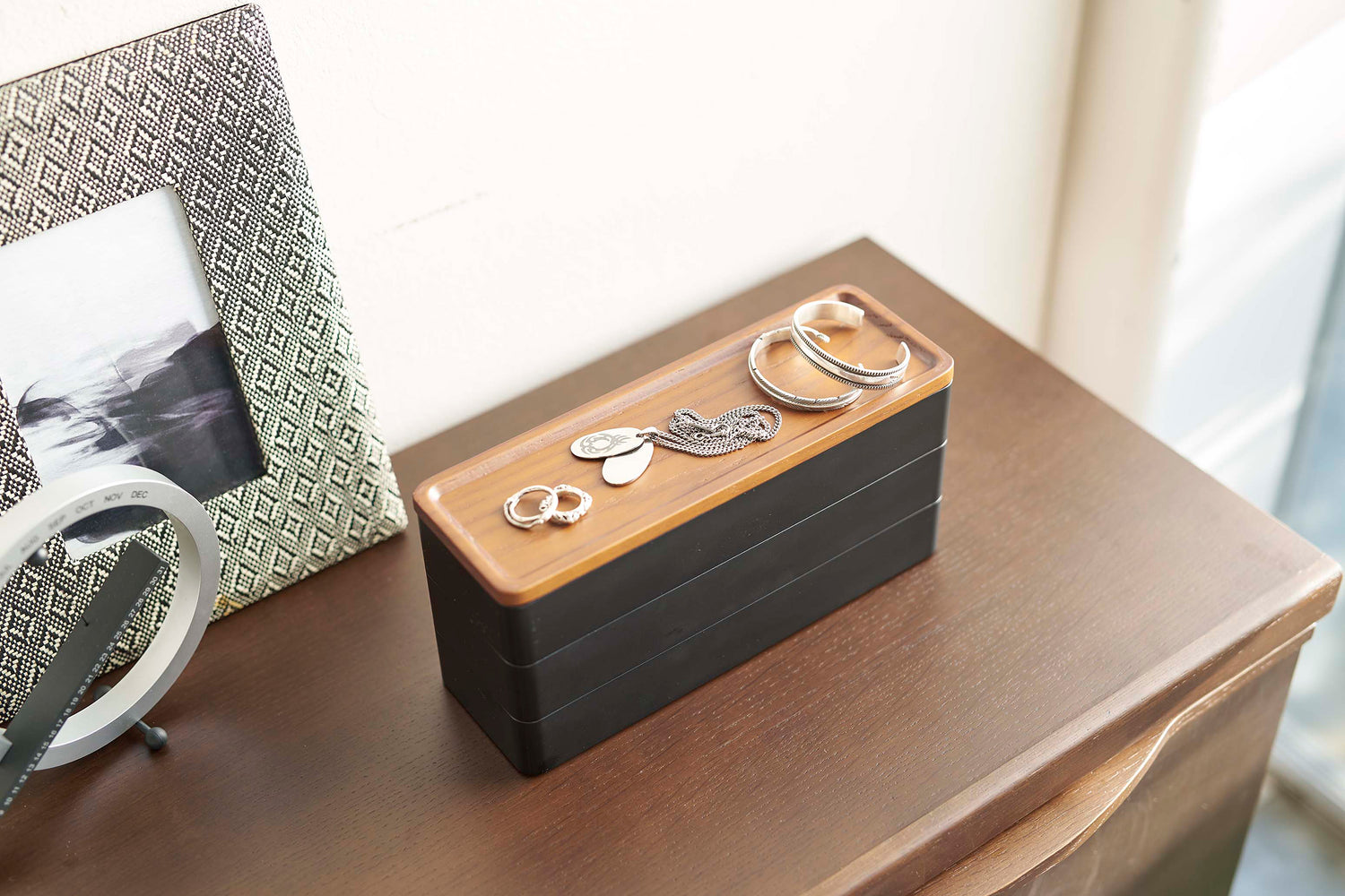View 14 - Black Stacking Watch and Accessory Case closed with jewelry on a chest of drawers