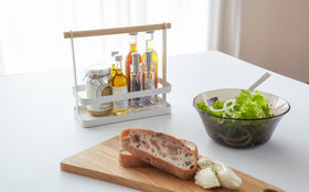 Front view of white Countertop Storage Caddy holding spices on kitchen table by Yamazaki Home. view 5
