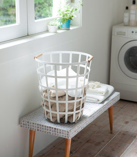 White Round Laundry Basket holding towels in laundry room by Yamazaki Home. view 3