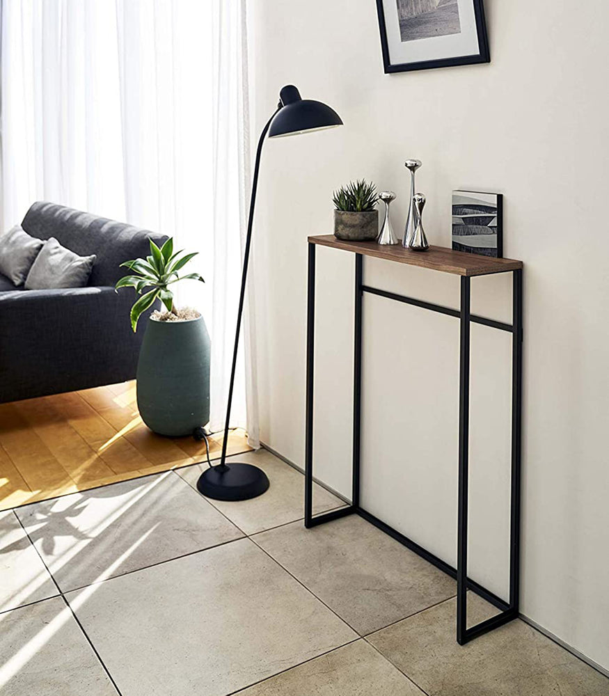 View 11 - Yamazaki Home Narrow Entryway Console Table with plants next a floor lamp. 