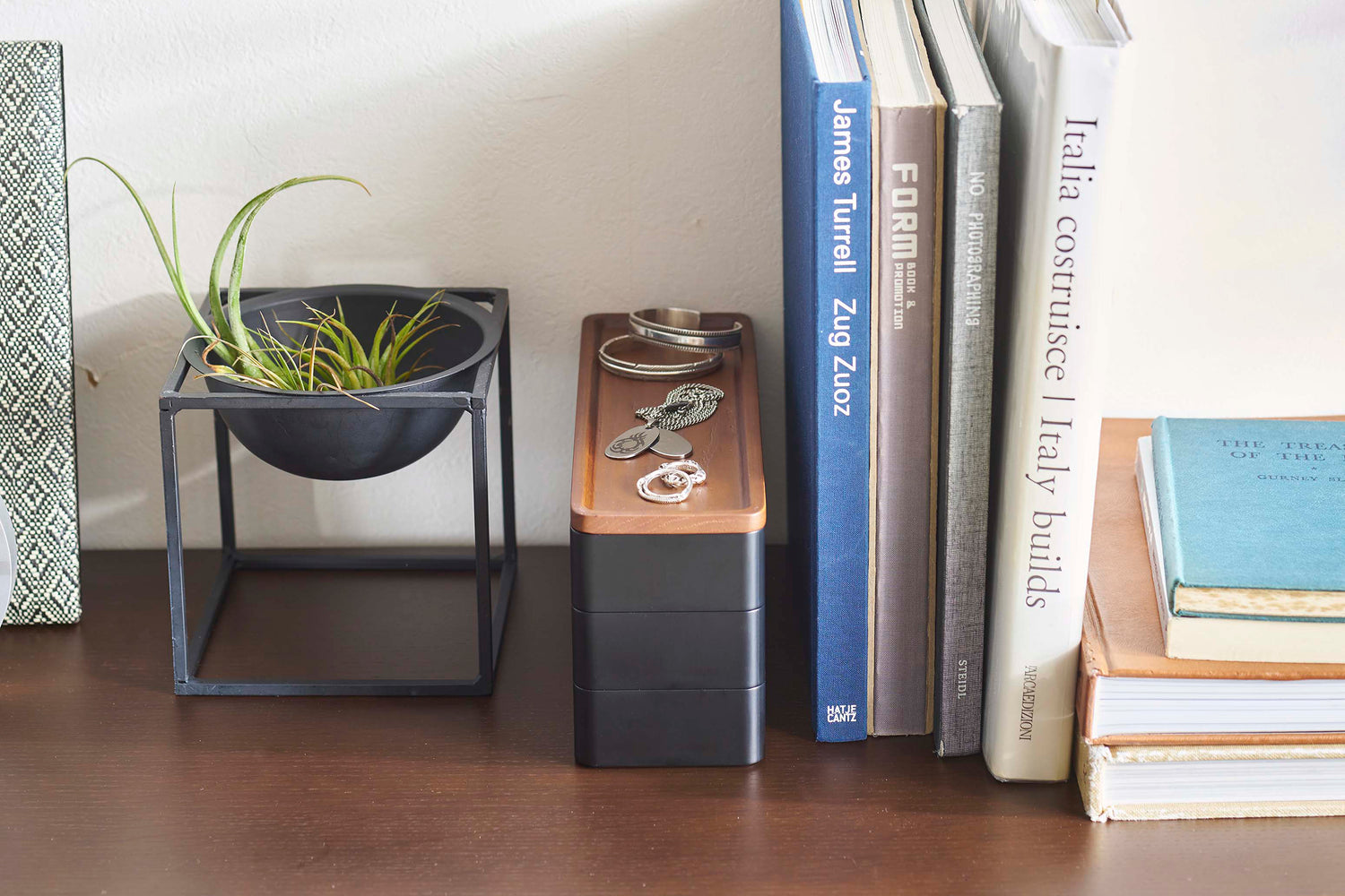 View 12 - Closed black Stacking Watch and Accessory Case in between books and plants with jewelry on top