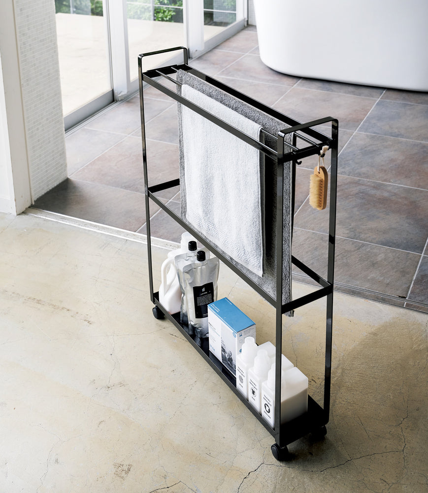 View 7 - Black Rolling Towel Rack holding towels and cleaning products by Yamazaki Home.