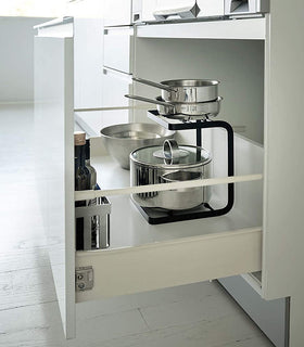 Side view of black 2-Tier Pot Holder with Hooks holding pots in kitchen drawer by Yamazaki Home. view 12