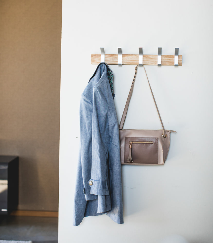 View 2 - Front view of ash Wall-Mounted Coat Hanger holding jacket and purse by Yamazaki Home.