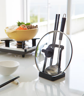 Black Lid & Ladle Stand displaying pot lid and cooking utensils in kitchen by Yamazaki Home. view 9