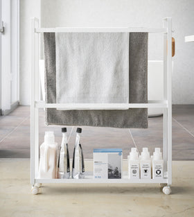 Front view of white Rolling Towel Rack holding towels and cleaning products by Yamazaki Home. view 5