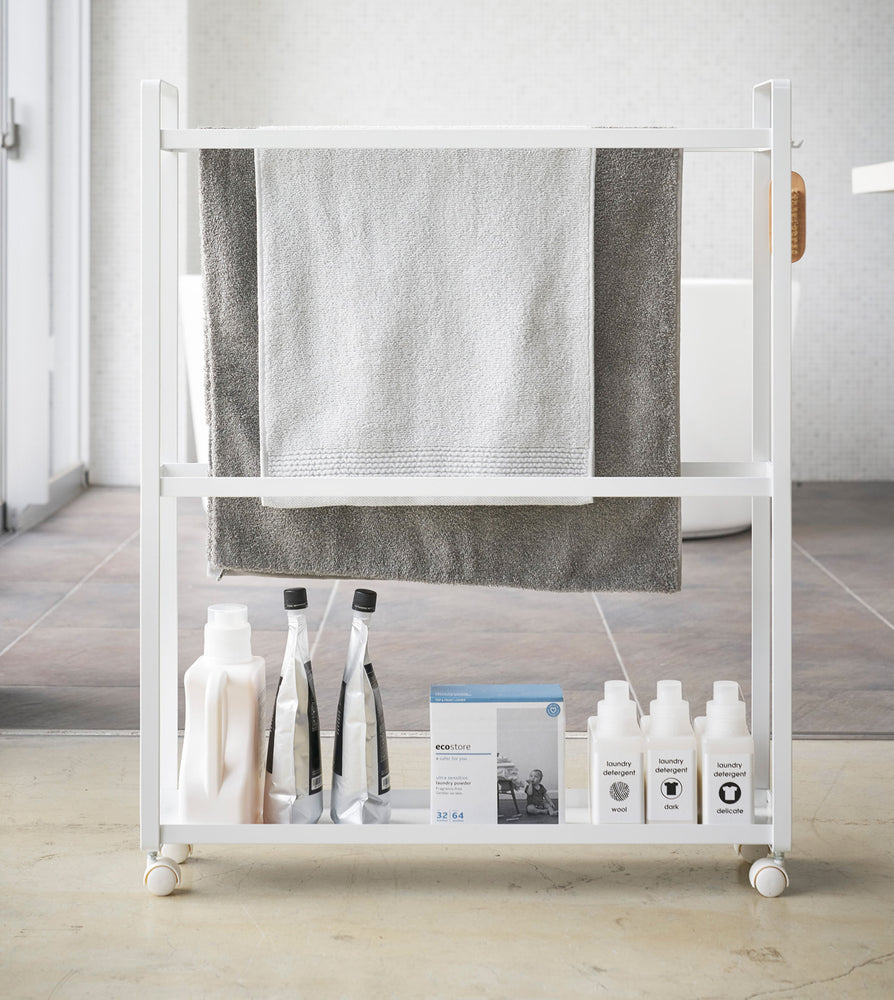 View 5 - Front view of white Rolling Towel Rack holding towels and cleaning products by Yamazaki Home.