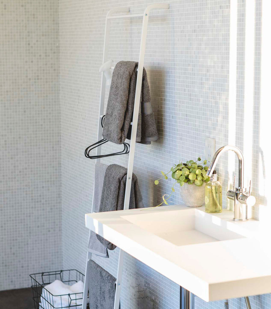 View 3 - Side view of white Leaning Ladder Rack holding towels in bathroom by Yamazaki Home.