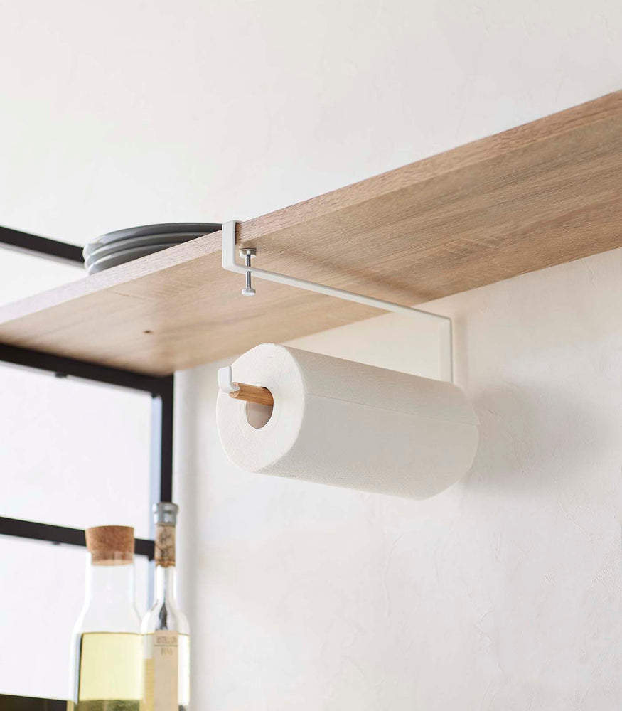 View 3 - Undershelf Paper Towel Holder attached to a shelf and holding paper towel roll by Yamazaki Home.