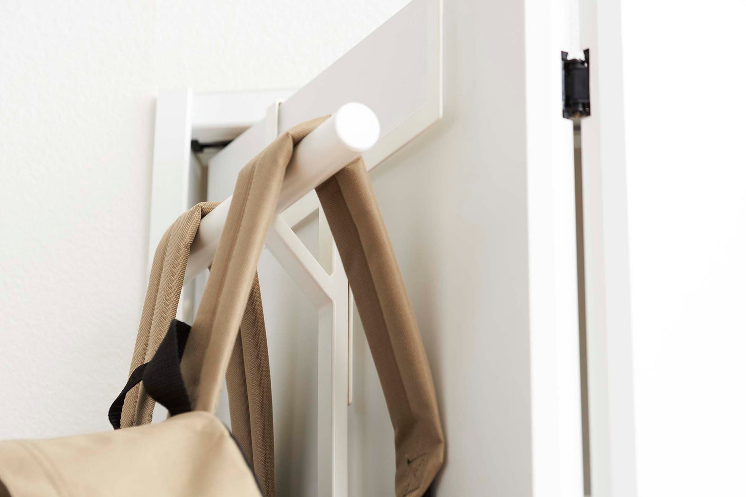 View 4 - Close up side view of White Kids' Backpack Hanger holding a backpack on door by Yamazaki Home.