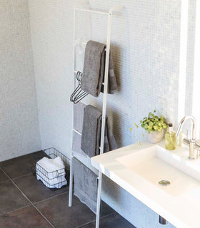 White Leaning Ladder Rack holding bath towels and hangers in bathroom by Yamazaki Home. view 5