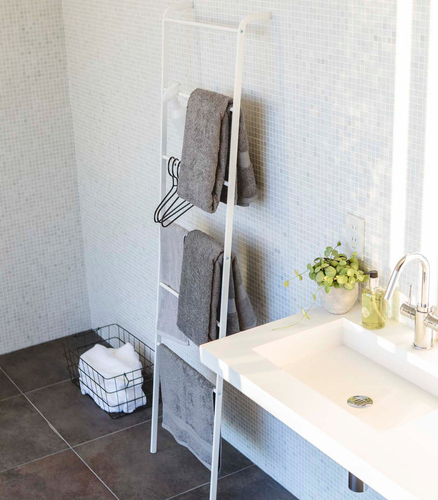View 5 - White Leaning Ladder Rack holding bath towels and hangers in bathroom by Yamazaki Home.