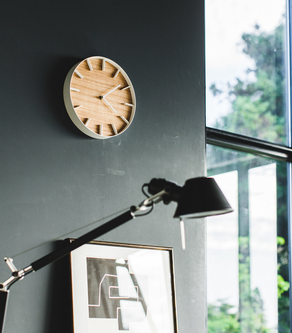 Angled side view of white Wall Clock in bedroom by Yamazaki Home.