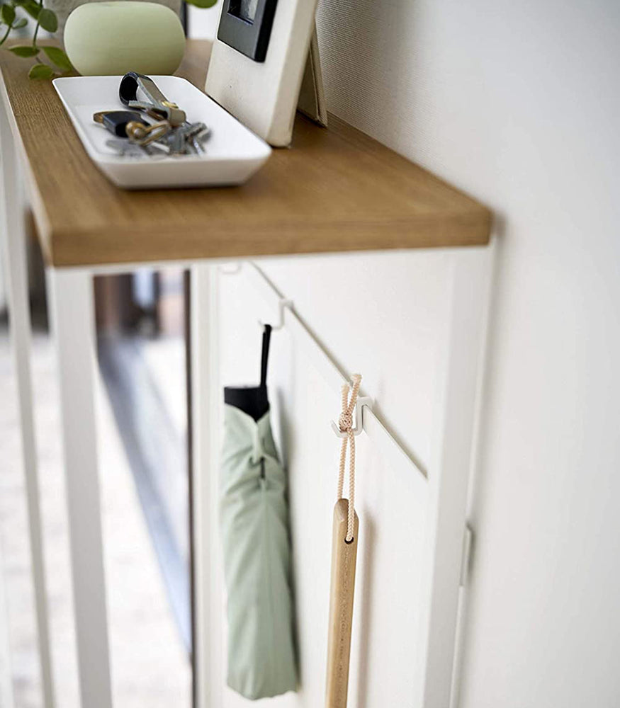 View 7 - Close up of Yamazaki Narrow Entryway Console Table in white holding keys and umbrellas. 