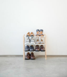 Front view of entryway Expandable Shoe Rack holding shoes by Yamazaki Home. view 3