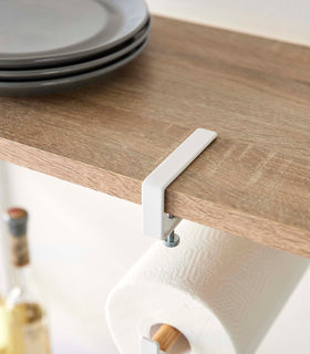 Close-up view of Undershelf Paper Towel Holder attachment hook on a shelf by Yamazaki Home. view 5