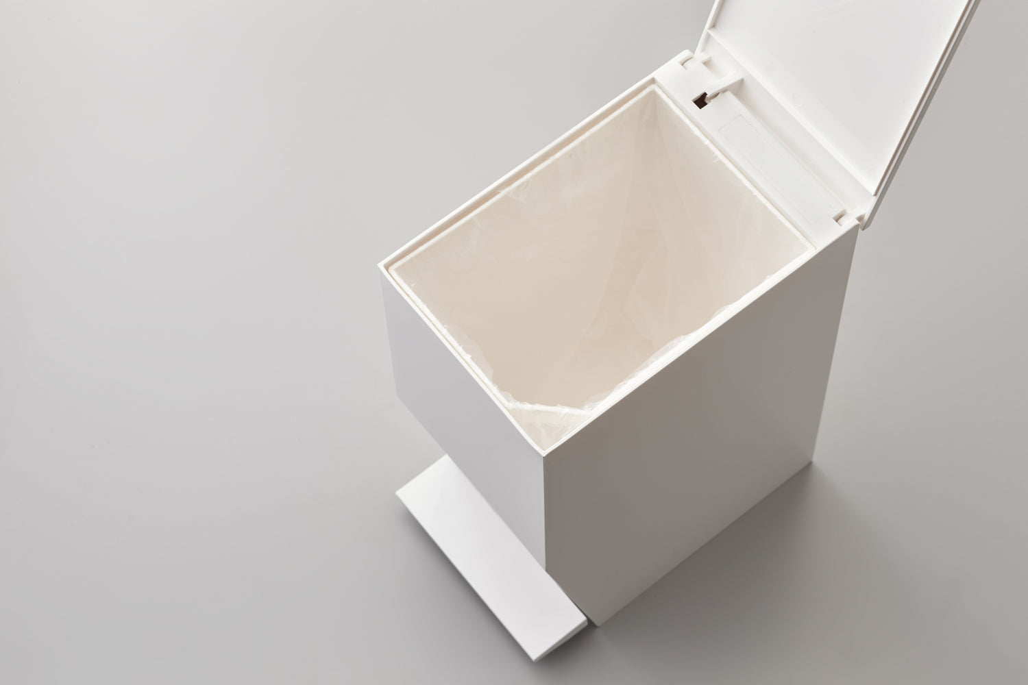 View 7 - Aerial view of white Step Trash Can open containing plastic bag on white background by Yamazaki Home.