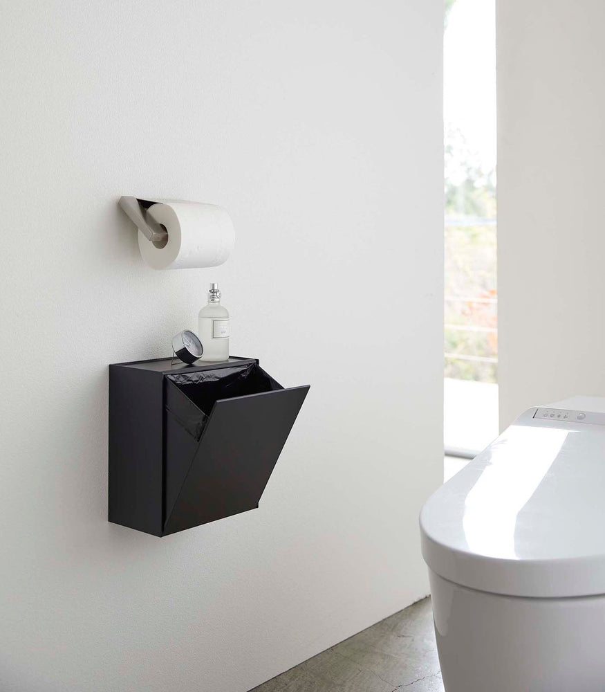 View 11 - Black Wall-Mount Storage open and holding trash bag on bathroom wall by Yamazaki Home.