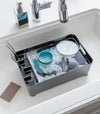 Black Dish Rack in kitchen sink holding water and dishes by Yamazaki Home.