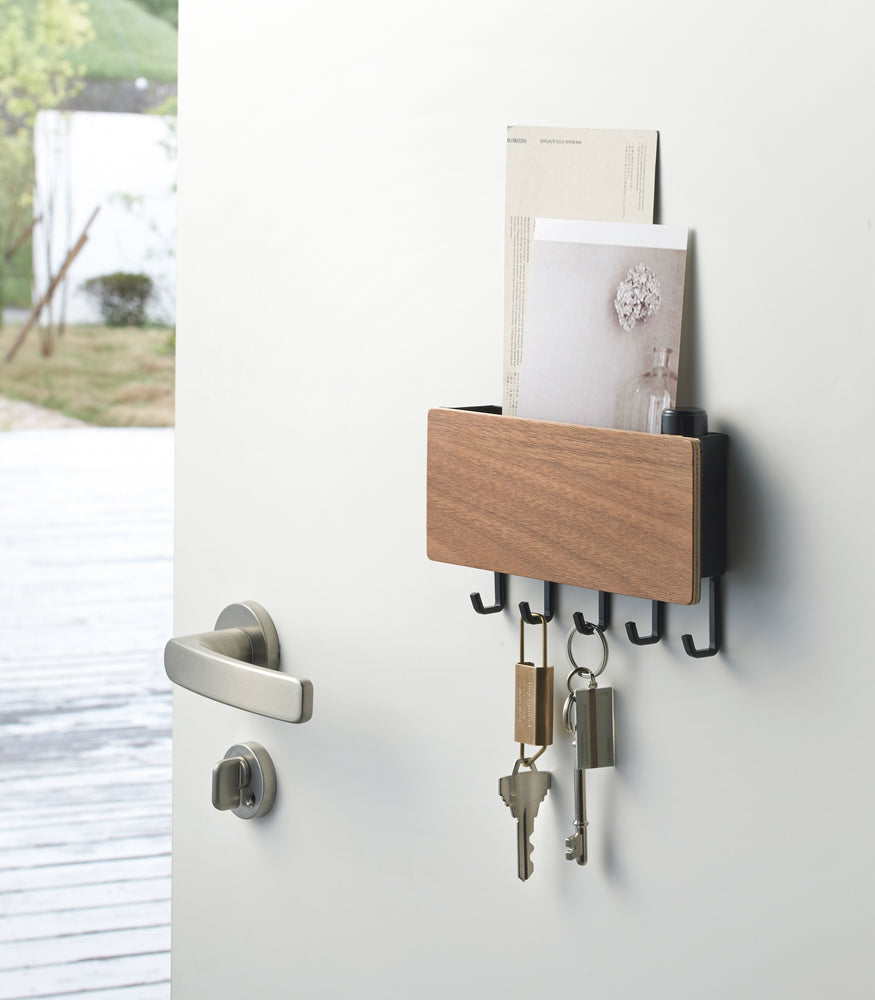 View 7 - Walnut Magnetic Key Rack with Tray holding paper and keys on door by Yamazaki Home.