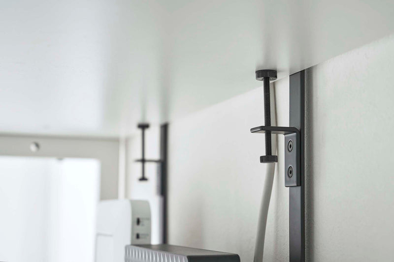 Close up under view of the black Wall-Mount Cable and Router Storage Rack by Yamazaki Home.