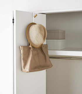 White Over-the-Door Hook on closet door holding hat and bag by Yamazaki Home. view 5