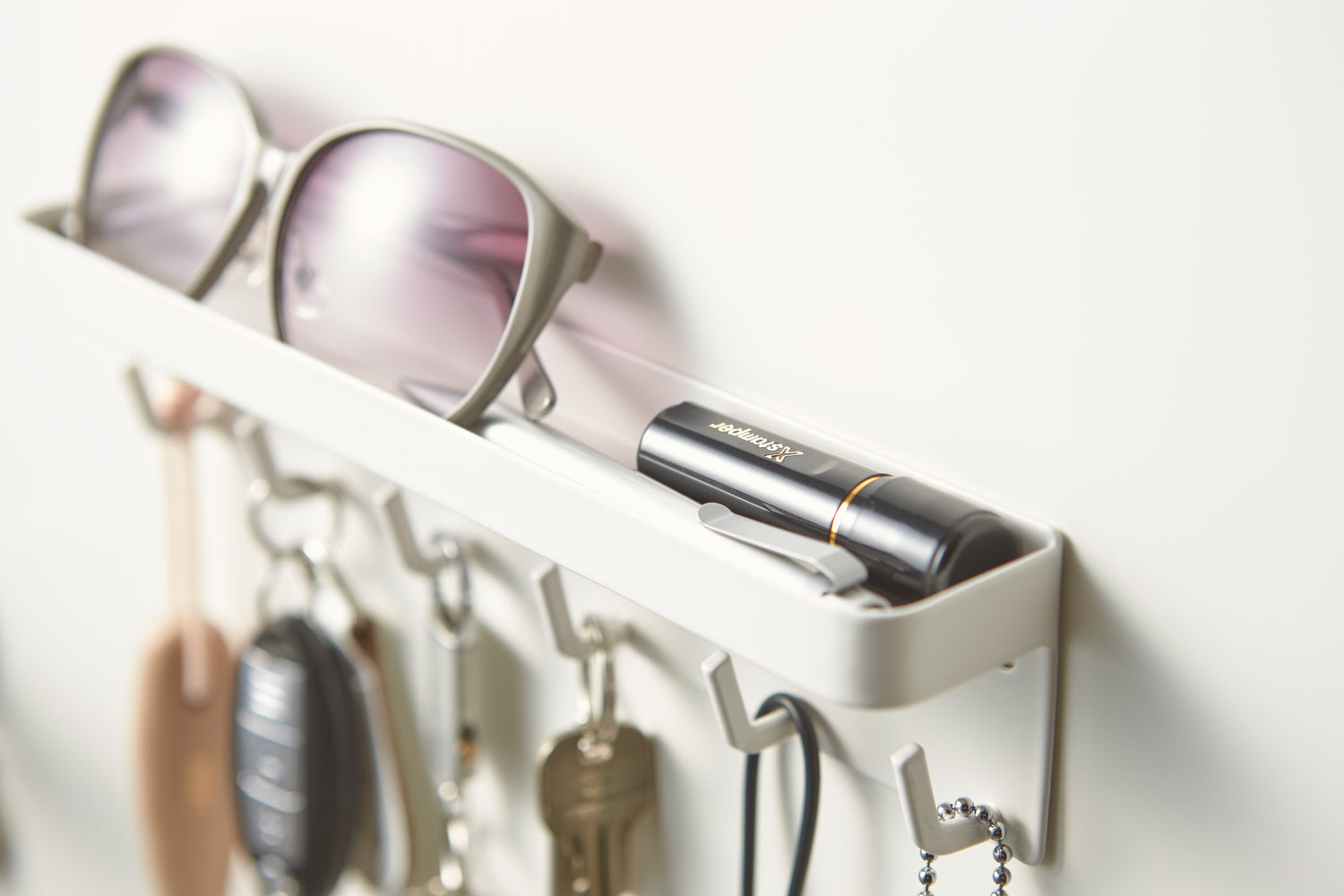 View 6 - Close up view of white Magnetic Key Rack with Tray holding keys and sunglasses by Yamazaki Home.