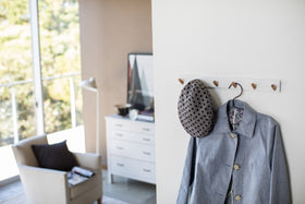 White Wall-Mounted Coat Hanger holding hat and jacket by Yamazaki Home. view 3