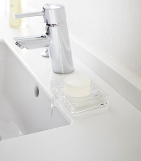 Clear Self-Draining Soap Tray holding soap on sink counter by Yamazaki Home. view 3