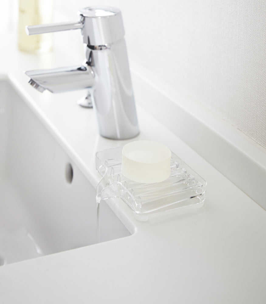 View 2 - Clear Self-Draining Soap Tray holding soap on sink counter by Yamazaki Home.