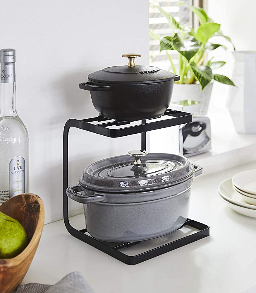 View 8 - Black 2-Tier Pot Holder with Hooks holding pots on kitchen countertop by Yamazaki Home.