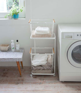 Front view of white Laundry Wagon and Basket holding clothes and towels in laundry room by Yamazaki Home. view 3