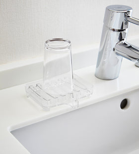 Clear Self-Draining Soap Tray holding soap bar on sink counter by Yamazaki Home. view 4